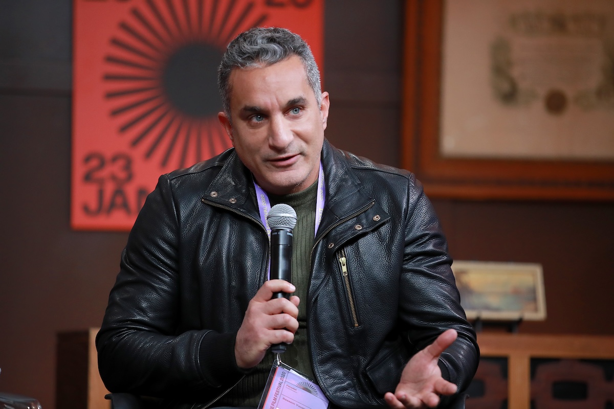 Bassem Youssef sitting with a microphone