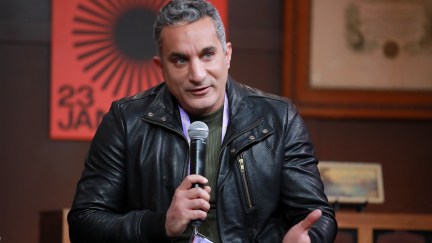 Bassem Youssef sitting with a microphone
