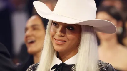 Beyonce smiles wearing a white cowboy hat.