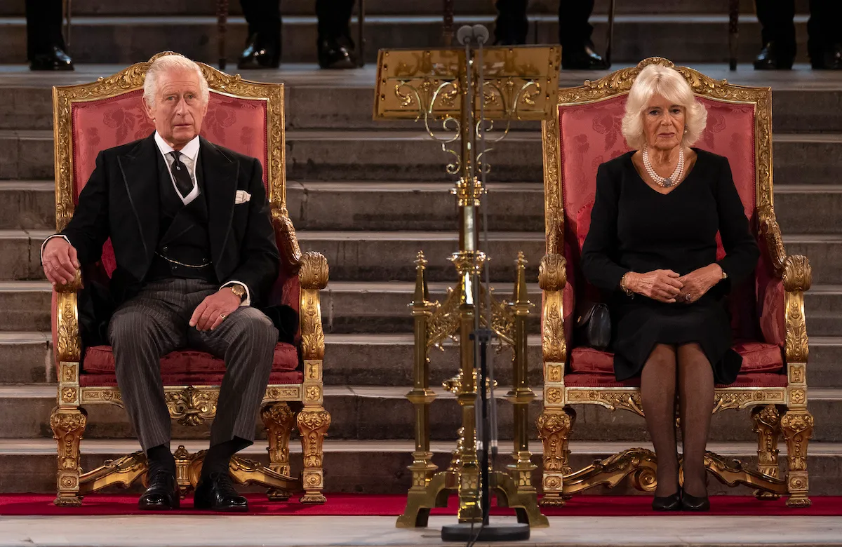 King Charles III and Camilla, Queen Consort sit on thrones.