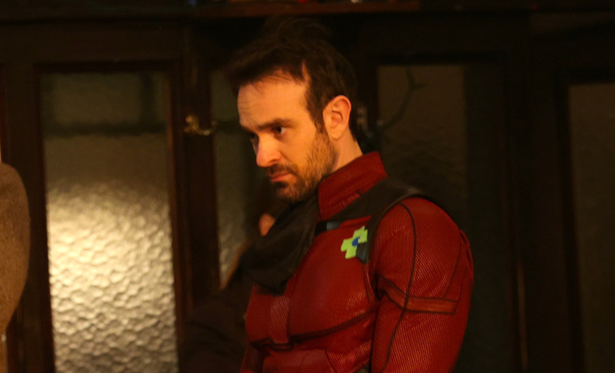 Charlie Cox frowns at something off camera, wearing his Daredevil suit.