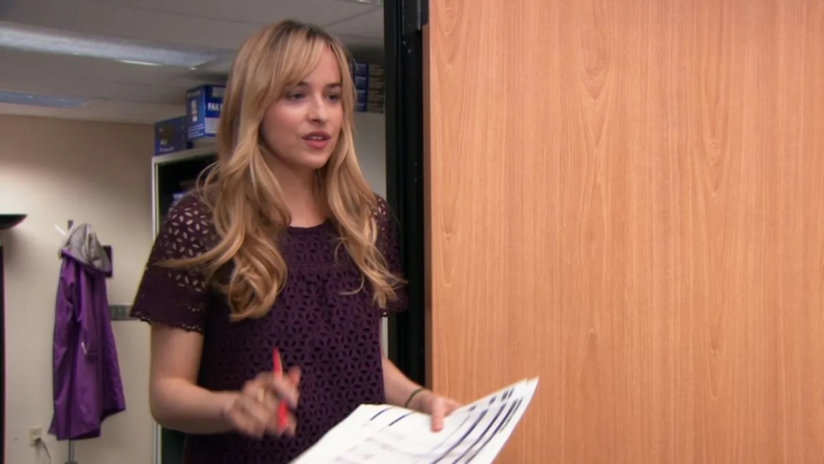 Dakota Johnson holding papers and walking into the door on the Office