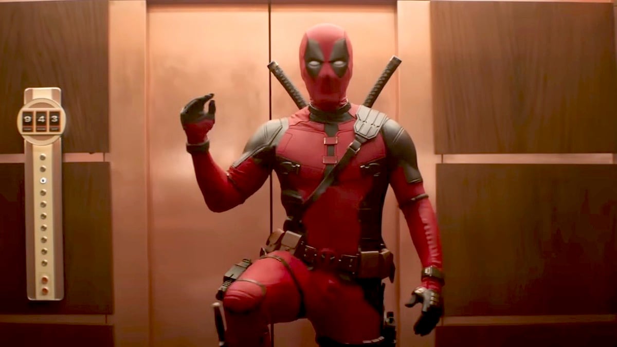 Deadpool pumps his fist and lifts one leg in an elevator.