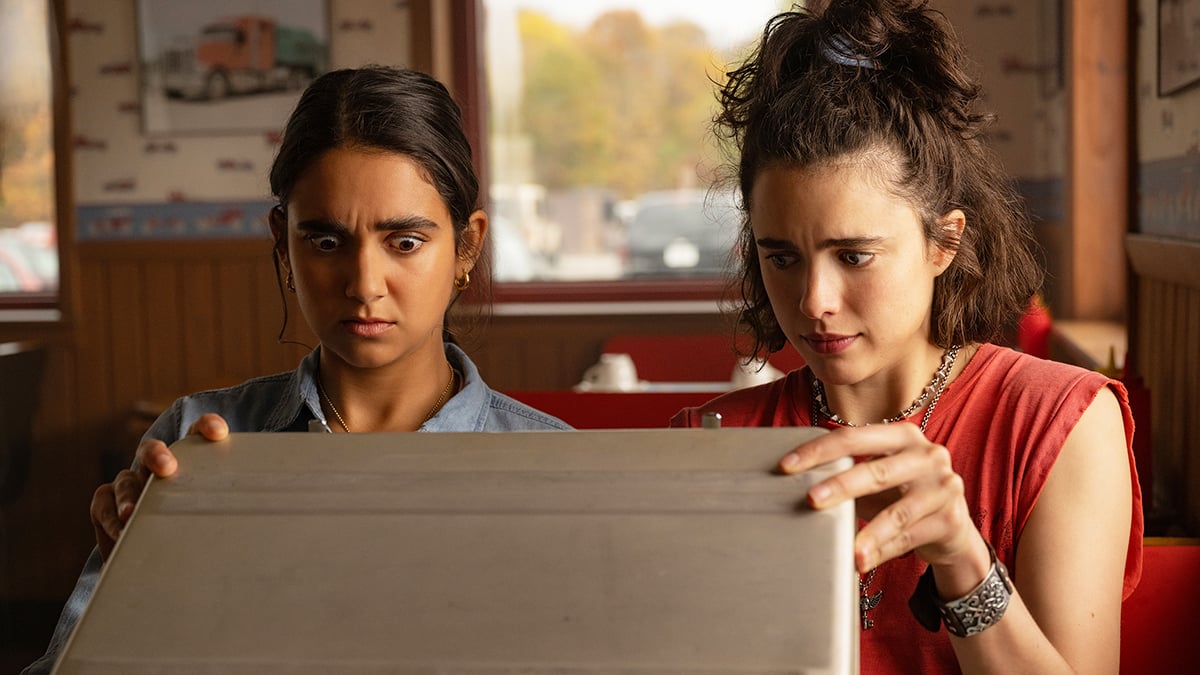 Margaret Qualley and Geraldine Viswanathan looking into a case in Drive-Away Dolls