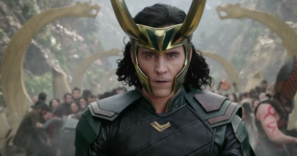 Loki wears his horns in Thor: Ragnarok, with other characters battling behind him.