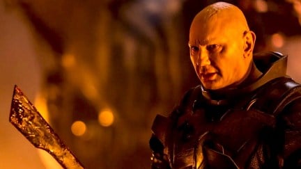 Dave Bautista as Rabban in Dune: Part Two, holding a large blade.