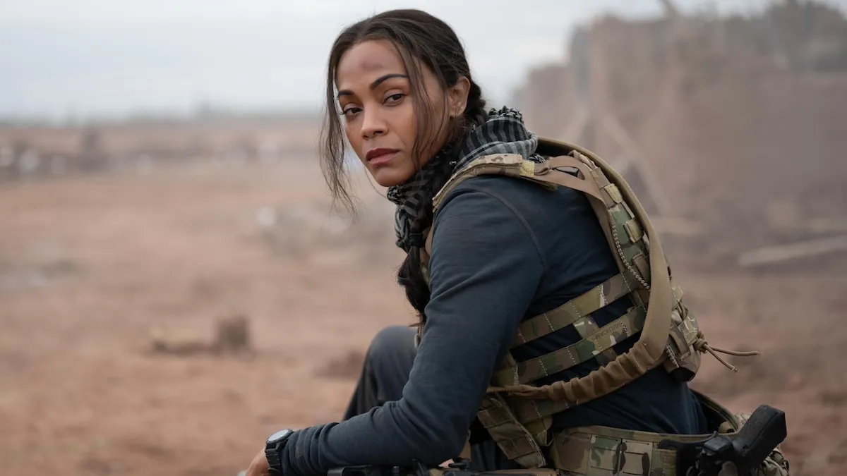 Zoe Saldaña sitting with a gun in the desert for 'Special Ops: Lioness'