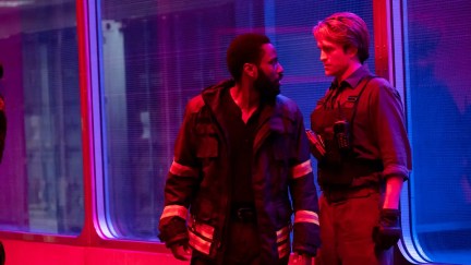 Robert Pattinson and John David Washington standing together in blue and red lighting