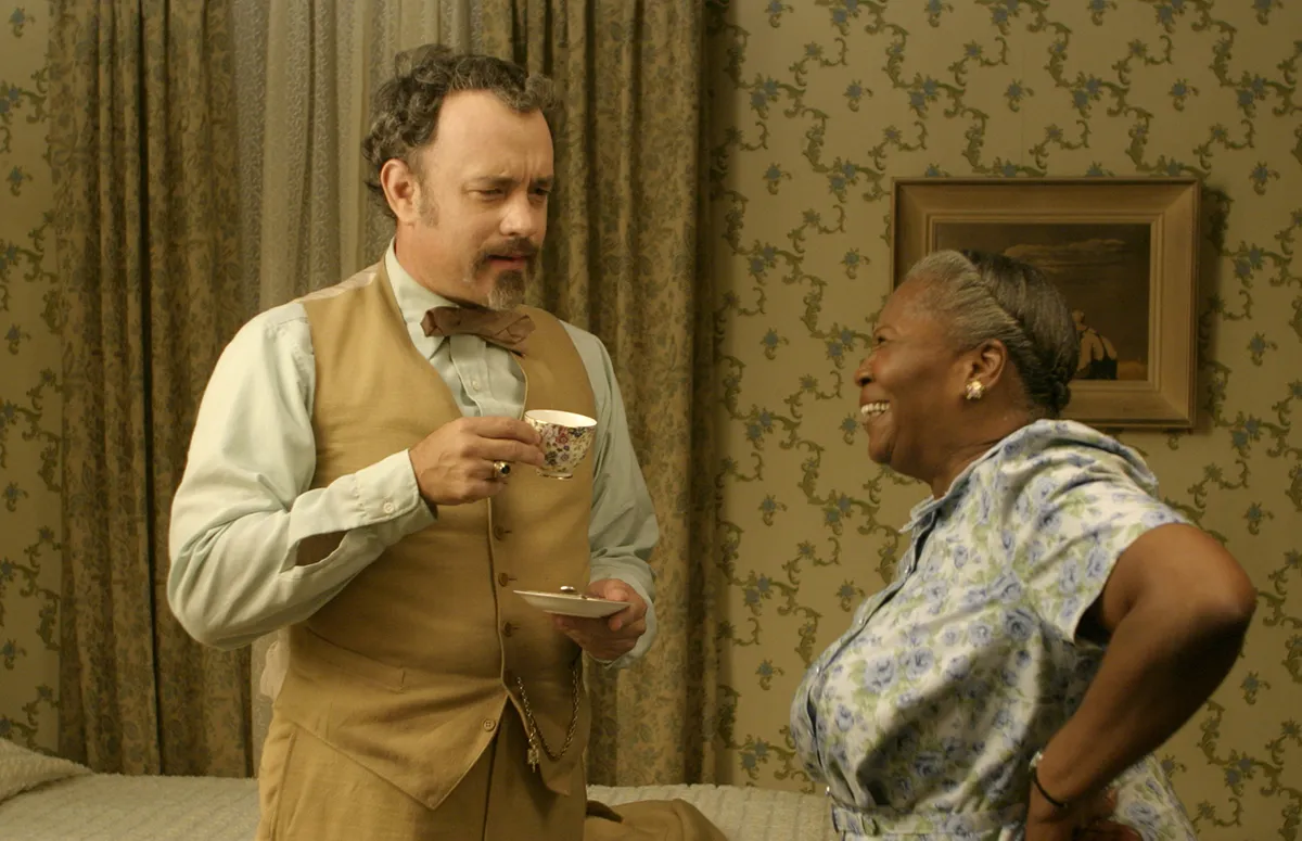 Tom Hanks standing with a cup of tea talking to Irma P. Hall in the Ladykillers