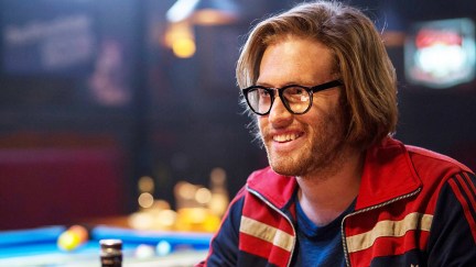 TJ Miller wearing glasses and sitting in a bar