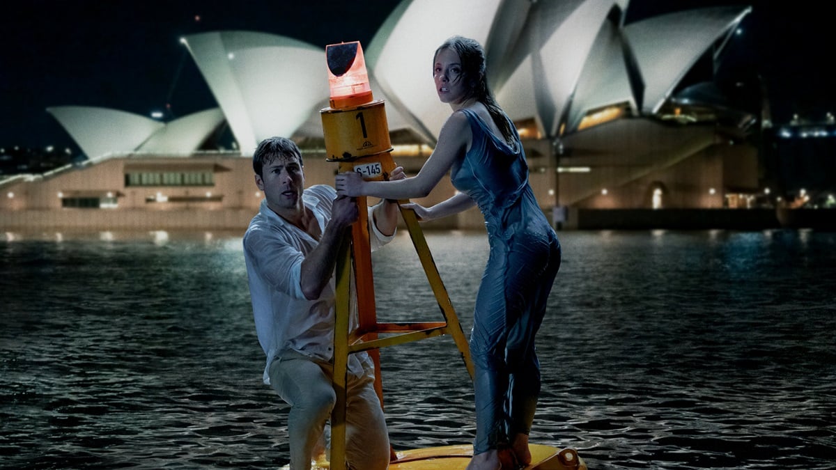 Glen Powell and Sydney Sweeney cling to a buoy in front of the Sydney Opera House in Anyone But You