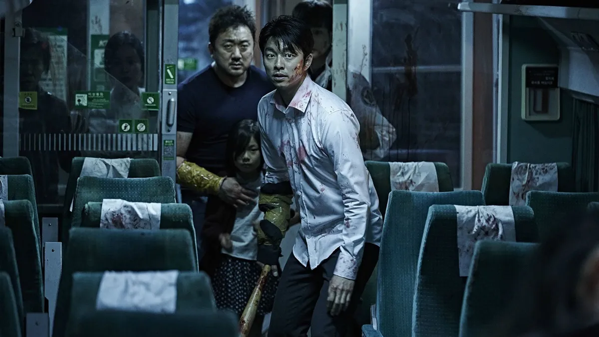 two bloodied men and a child look terrified on a train