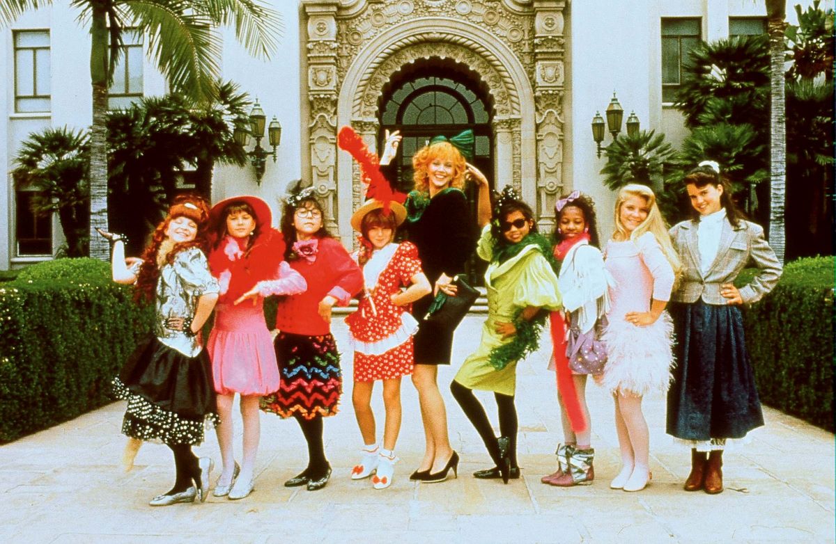 Photo of the cast of 'Troop Beverly Hills.' Shelly Long as Phyllis is in the center flanked by four tween girls on her left and four tween girls on her right. They are all dressed in stylish 1980s outfits.