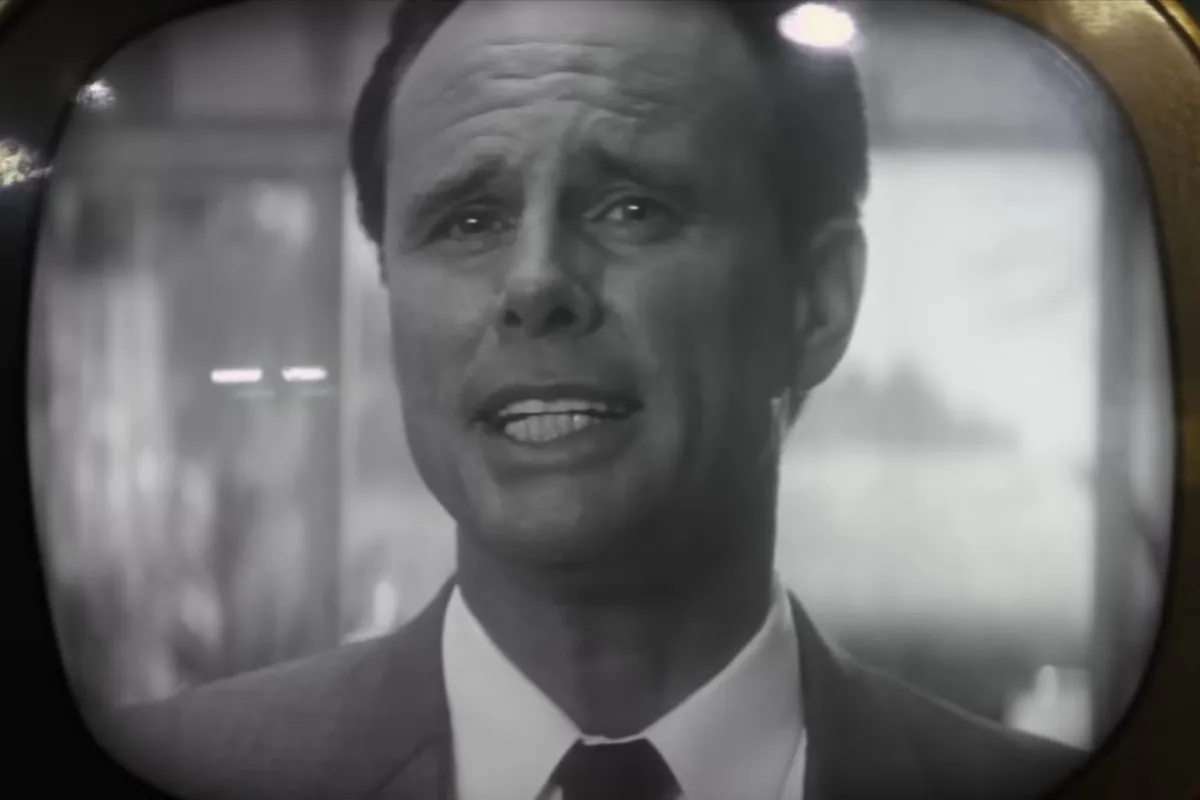 Screencap of Walton Goggins in a scene from 'Fallout.' He is a white man on a black and white TV screen with slicked back dark hair and wearing a white buttondown and tie under a grey suit jacket.