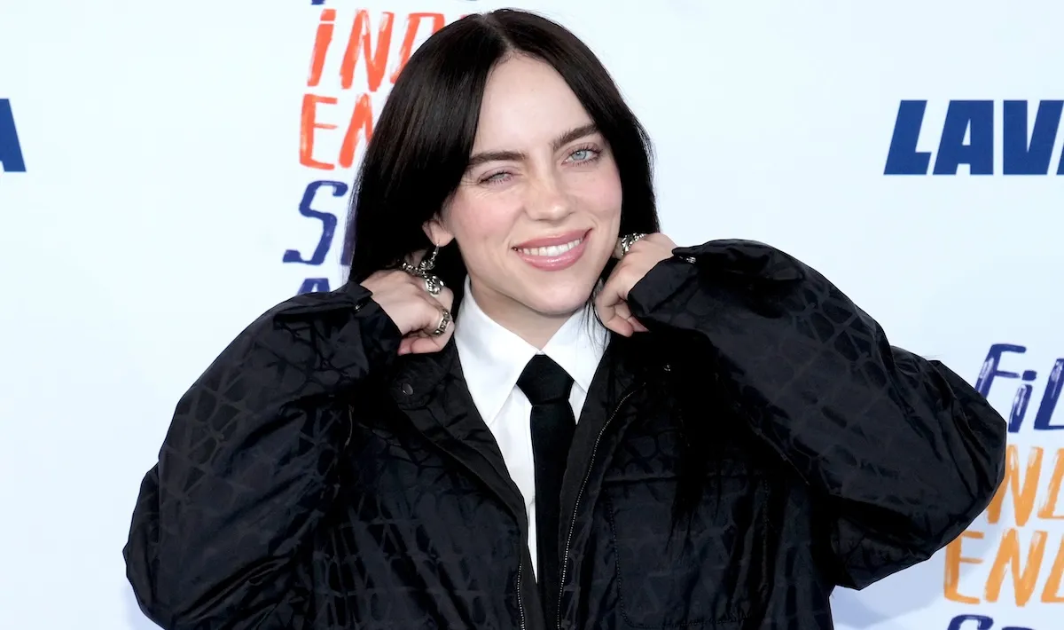 Billie Eilish winking at the camera on a red carpet