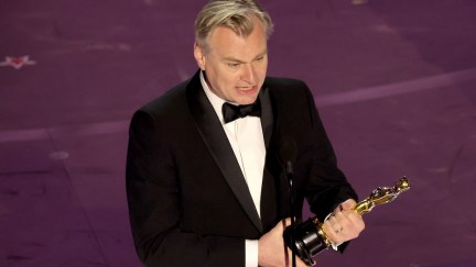 Christopher Nolan standing on stage with his Oscar