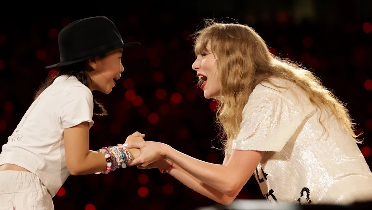 Taylor Swift and a fan hold hands at The Eras Tour.