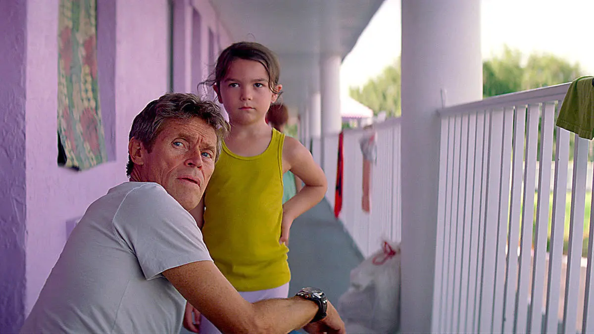 A hotel manager looks over his shoulder while talking to a young girl in "The Florida Project" 