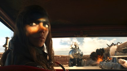 Furiosa looks over her shoulder while backing up a truck.