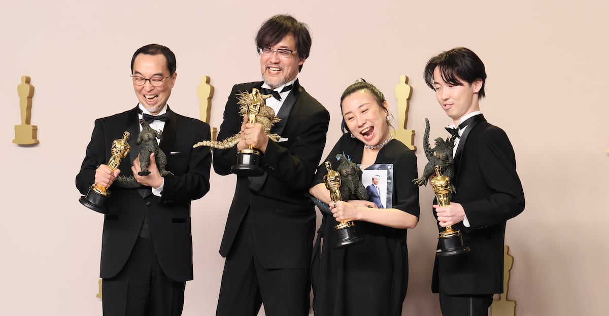 The visual effects team for Godzilla Minus One holds up their Oscars and toy Godzillas.