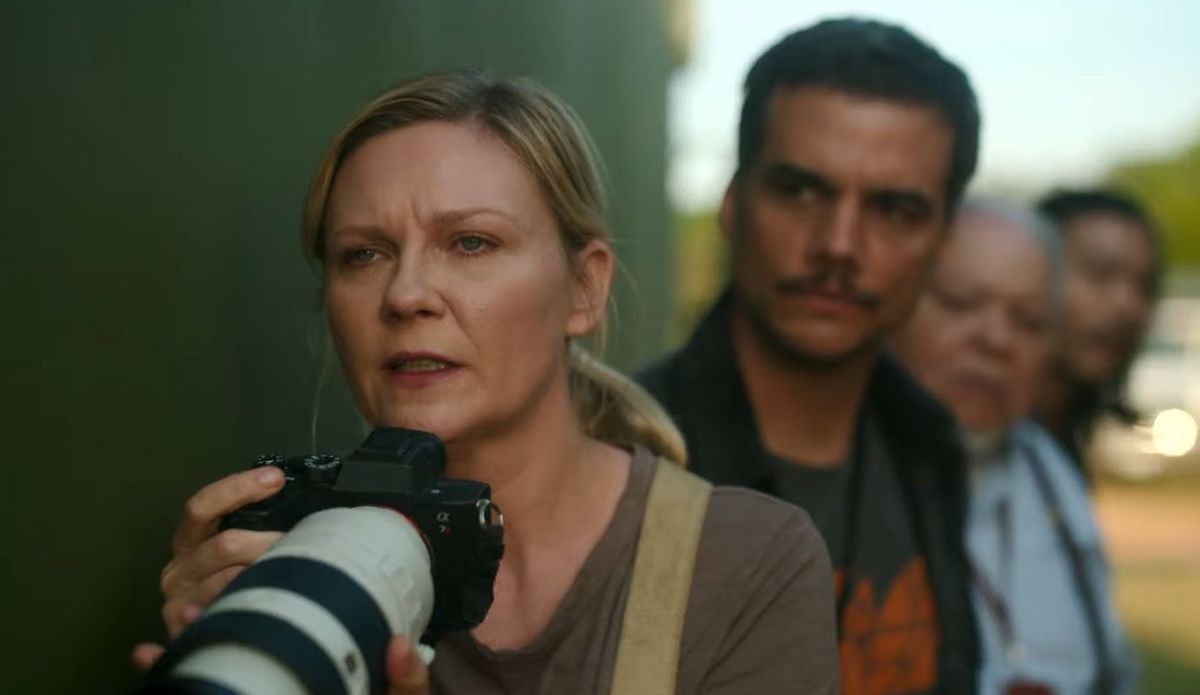 Kirsten Dunst as Lee Smith, holding up a camera in Civil War.