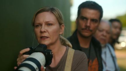 Kirsten Dunst as Lee Smith, holding up a camera in Civil War.