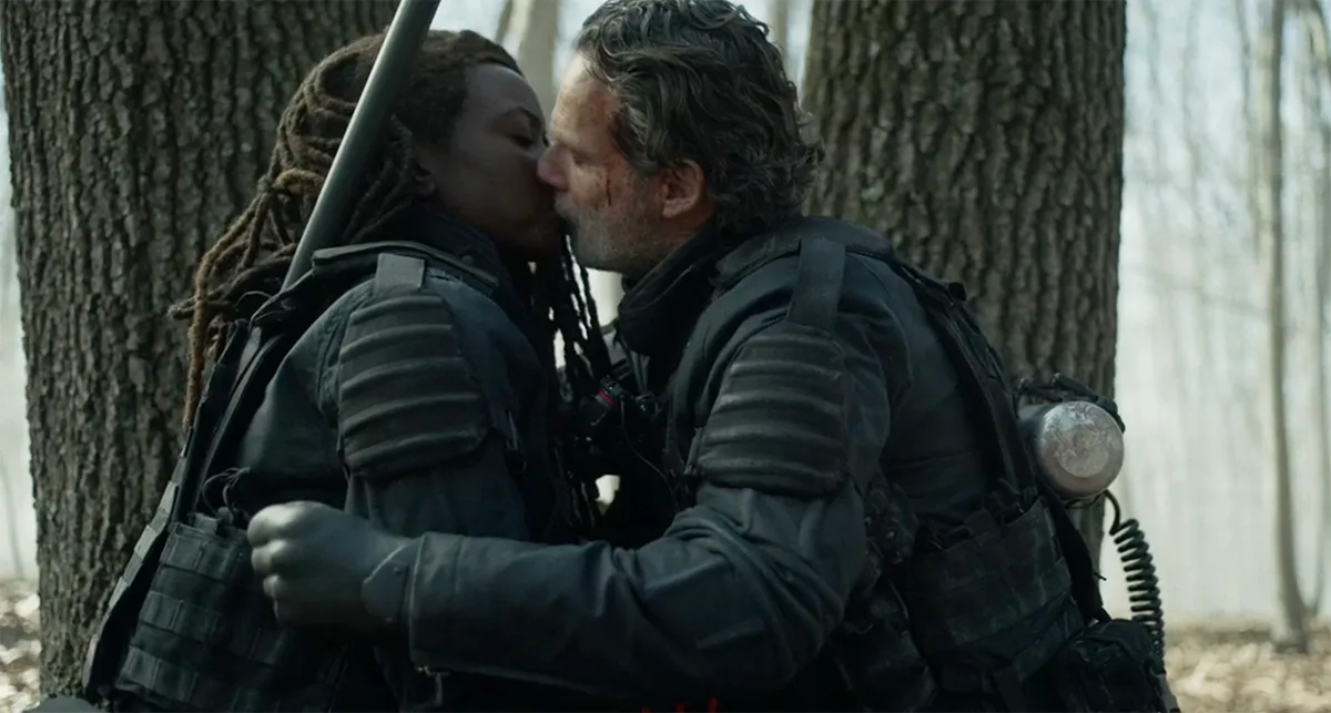 Michonne and Rick Grimes kissing each other by some trees