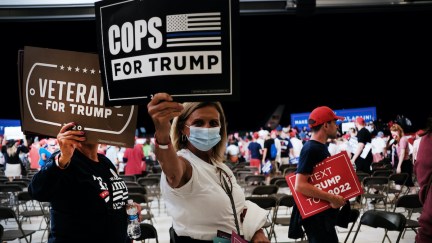 Attendees of the RNC in 2020 hold signs supporting Trump.