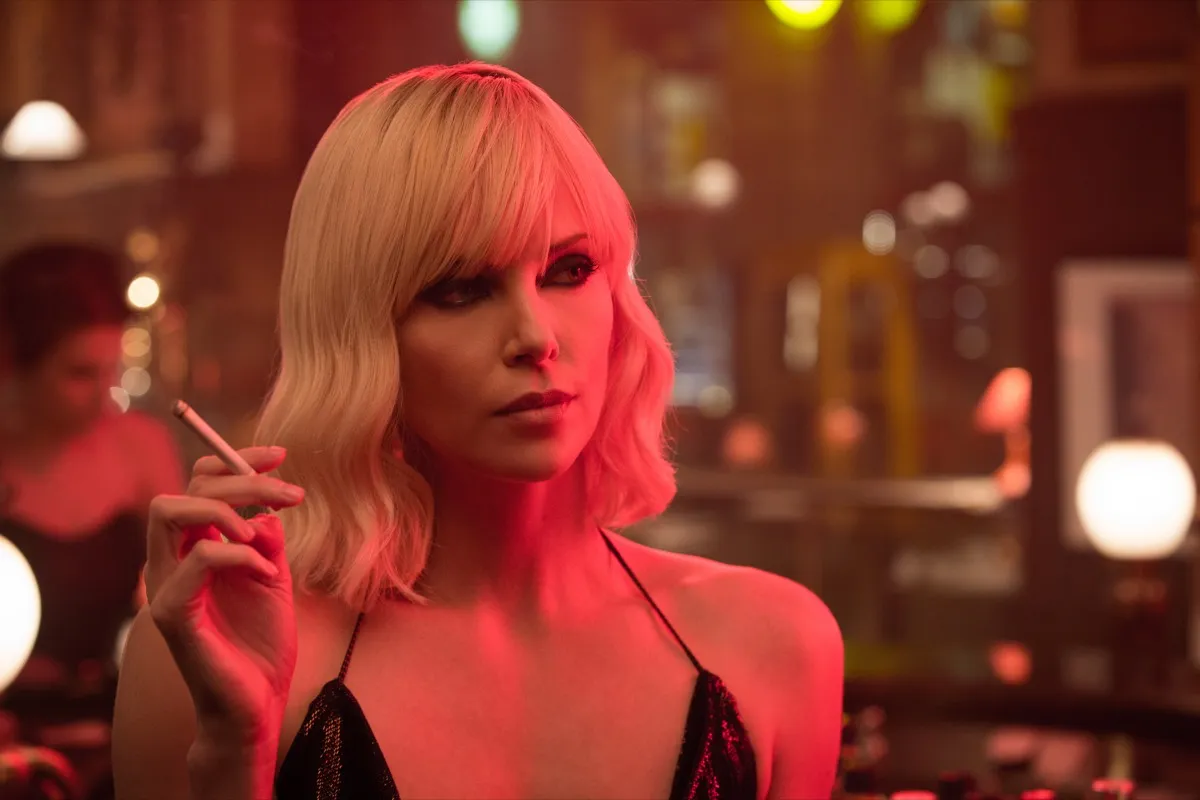A blonde woman in a cocktail dress smokes a cigarette in "Atomic Blonde" 