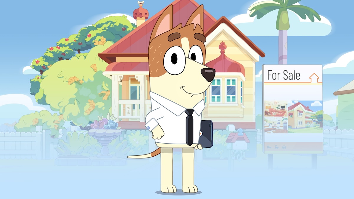 Bucky Dunston, a dog in a shirt and tie, stands in front of the Heelers' house.