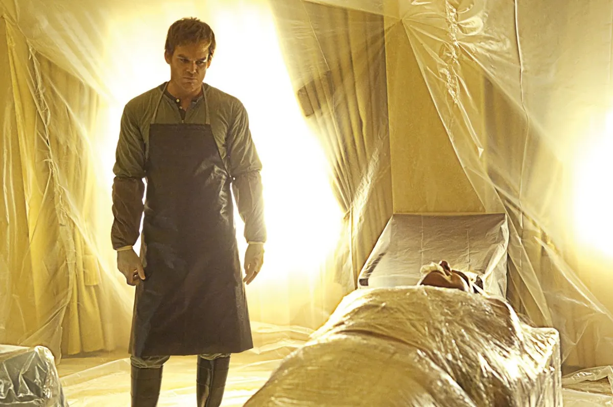 Michael C. Hall as Dexter standing in a plastic-wrapped room with a body on the table