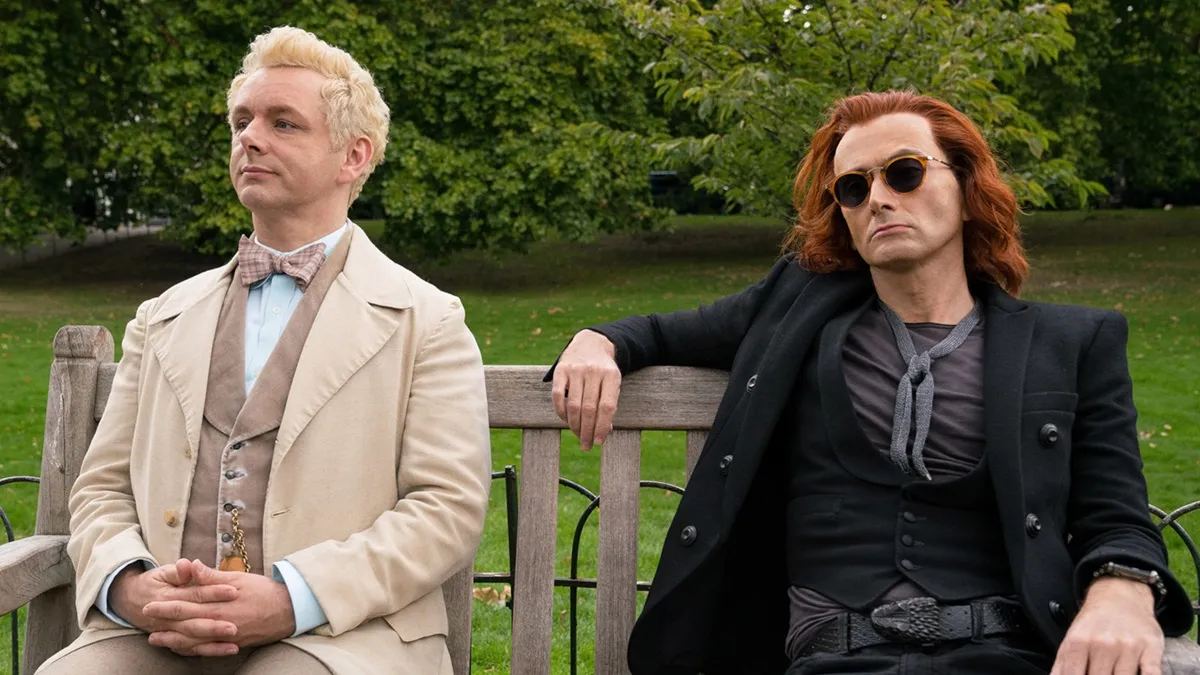 Michael Sheen and David Tennant sit on a bench in Good Omens
