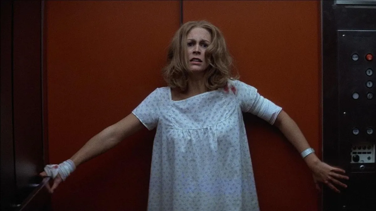 An exhausted woman leans up against a wall in a hospital gown in "Halloween II"