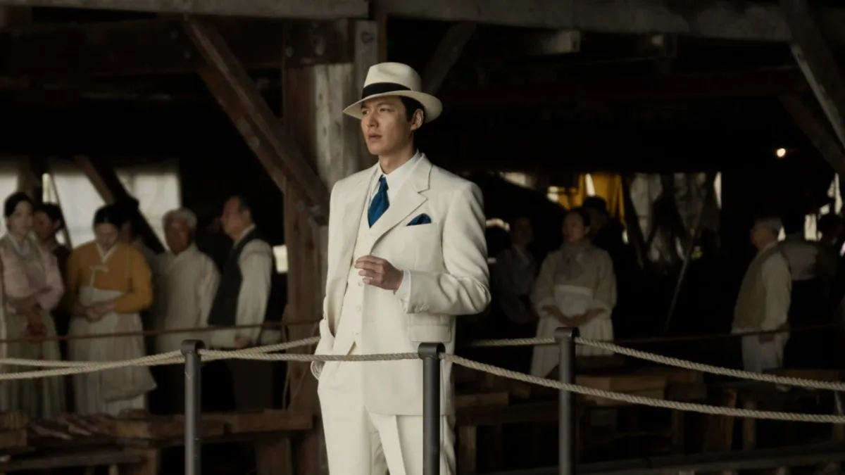 Pachinko, Hansu played by Lee Min-Ho, stands on a dock with a white suit and hat