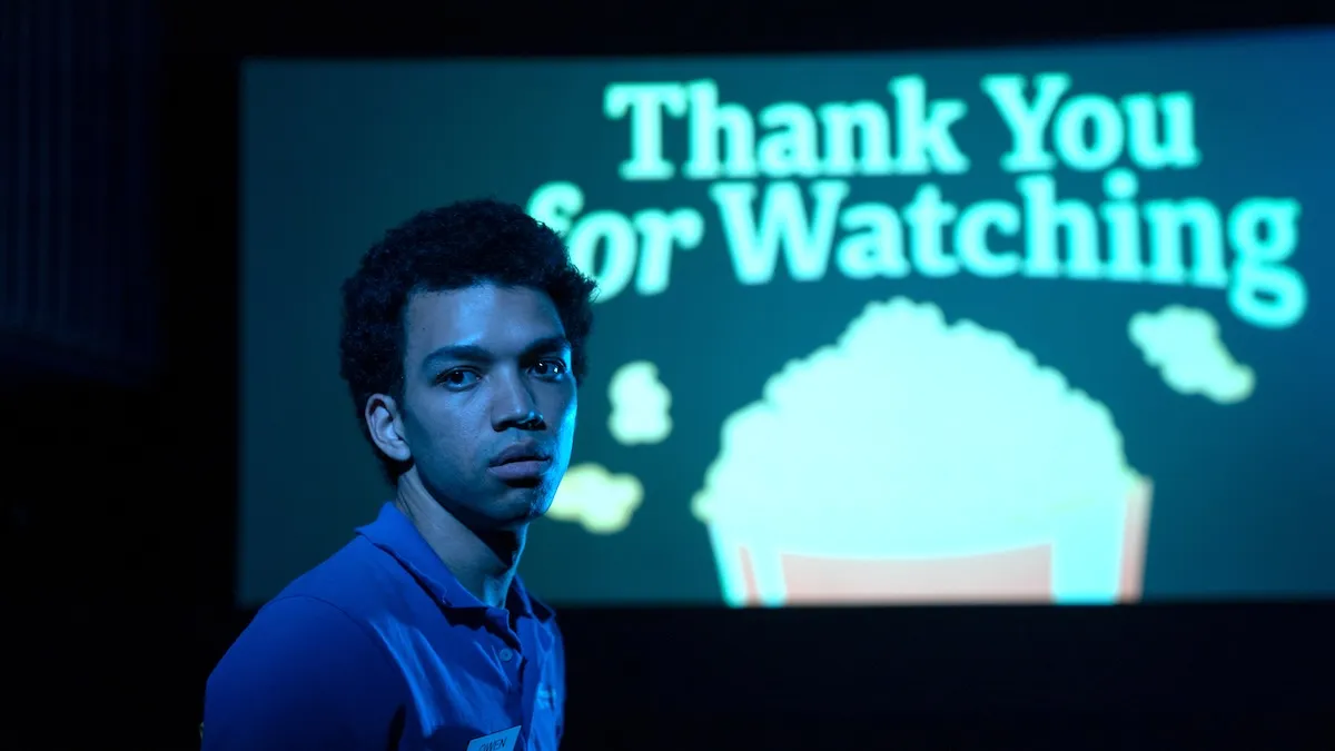 Owen (Justice Smith) stands in front of a movie screen that says "Thank you for watching."