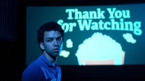 Owen (Justice Smith) stands in front of a movie screen that says 