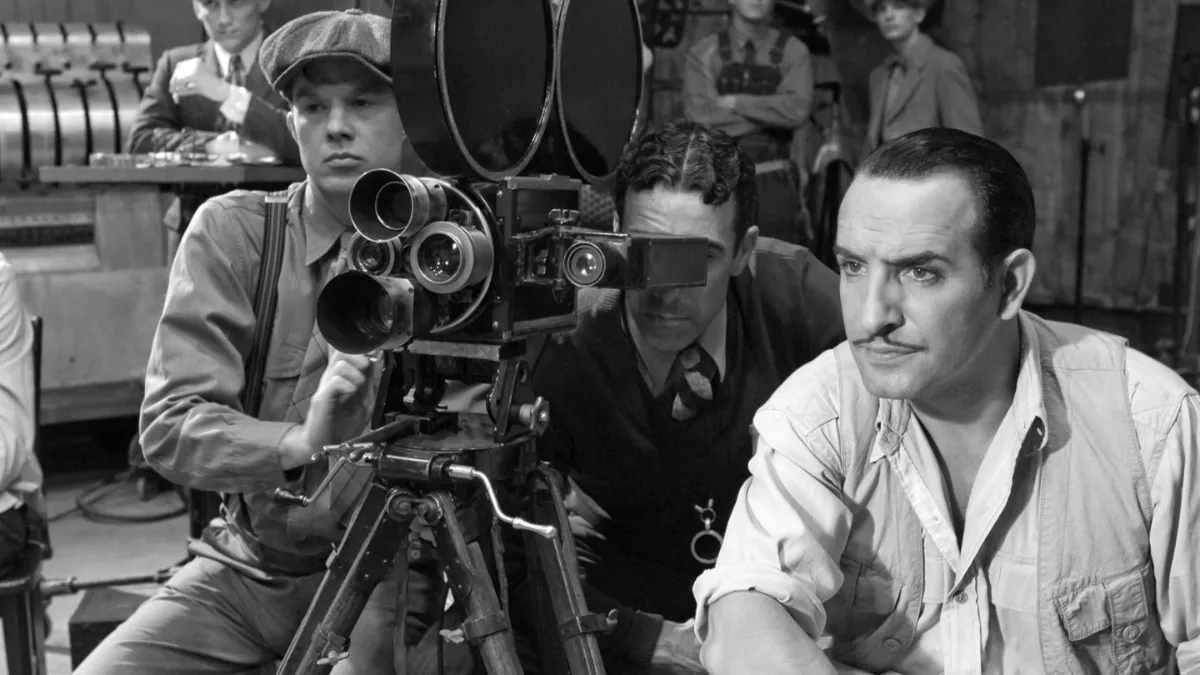 The Artist, starring Jean Dujardin. image in balck and white and Dujardin's character sits in front of a 1930s film character