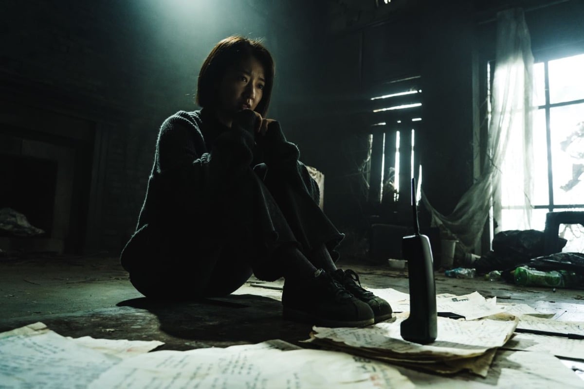 A woman sits and stares at a cordless phone on the floor in "The Call"