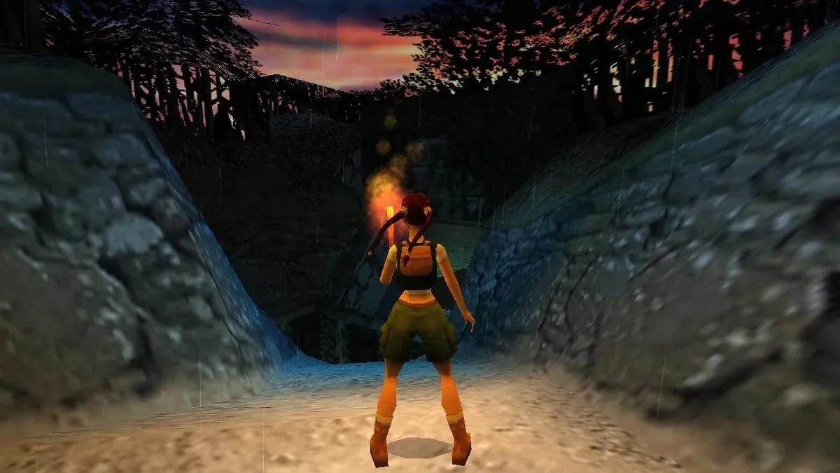 Lara Crofts stands in a ravine in torchlight