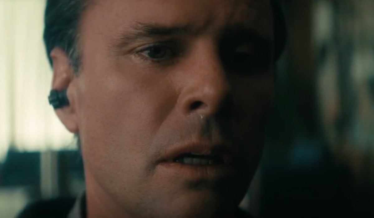 Close-up of Walton Goggins as Cooper Howard in Prime Video's 'Fallout.' He is a white man with short, dark hair. He is listening to an earpiece and crying, looking horrified.