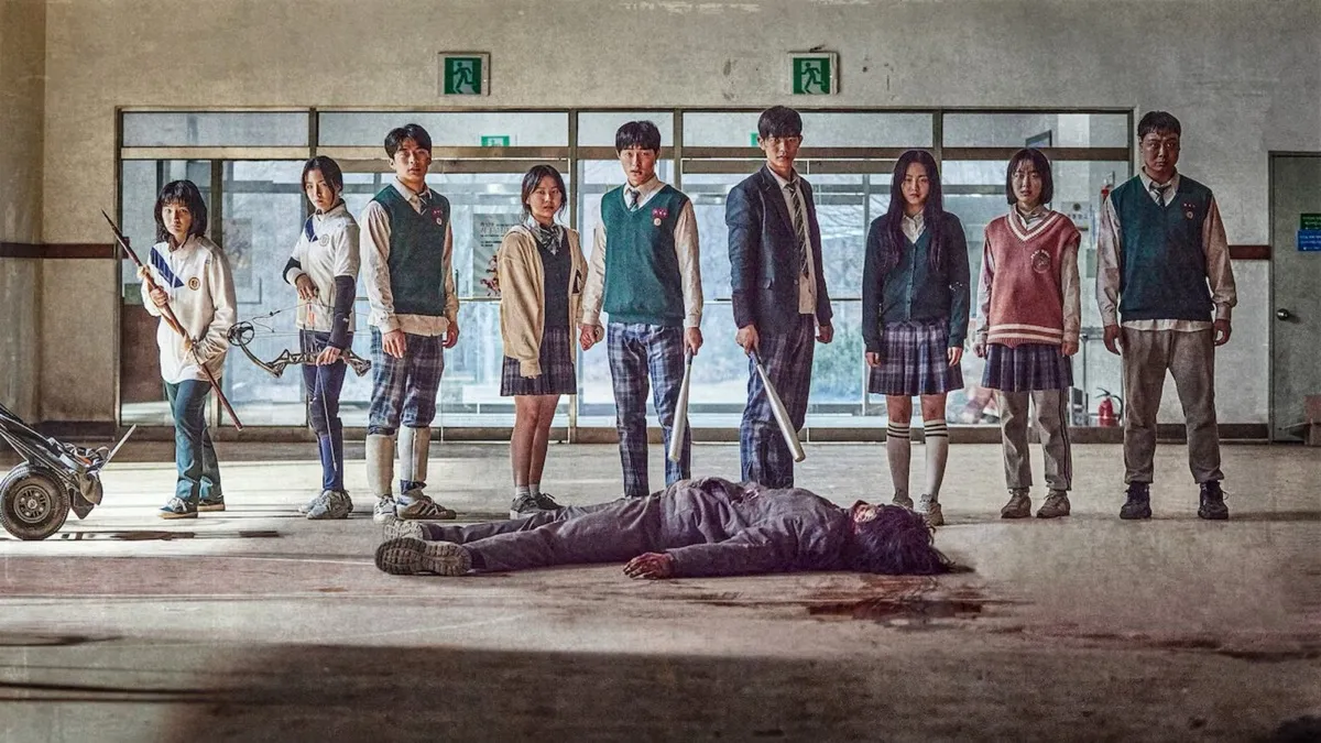A group of weapon holding teens stand around a zombie's corpse in "All of us are dead" 