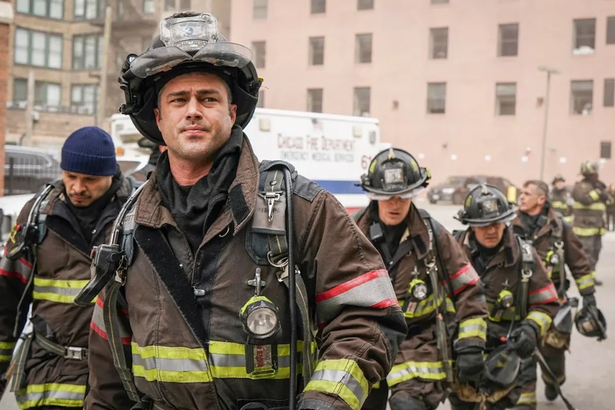 The cast of Chicago Fire all standing in their firefighter gear