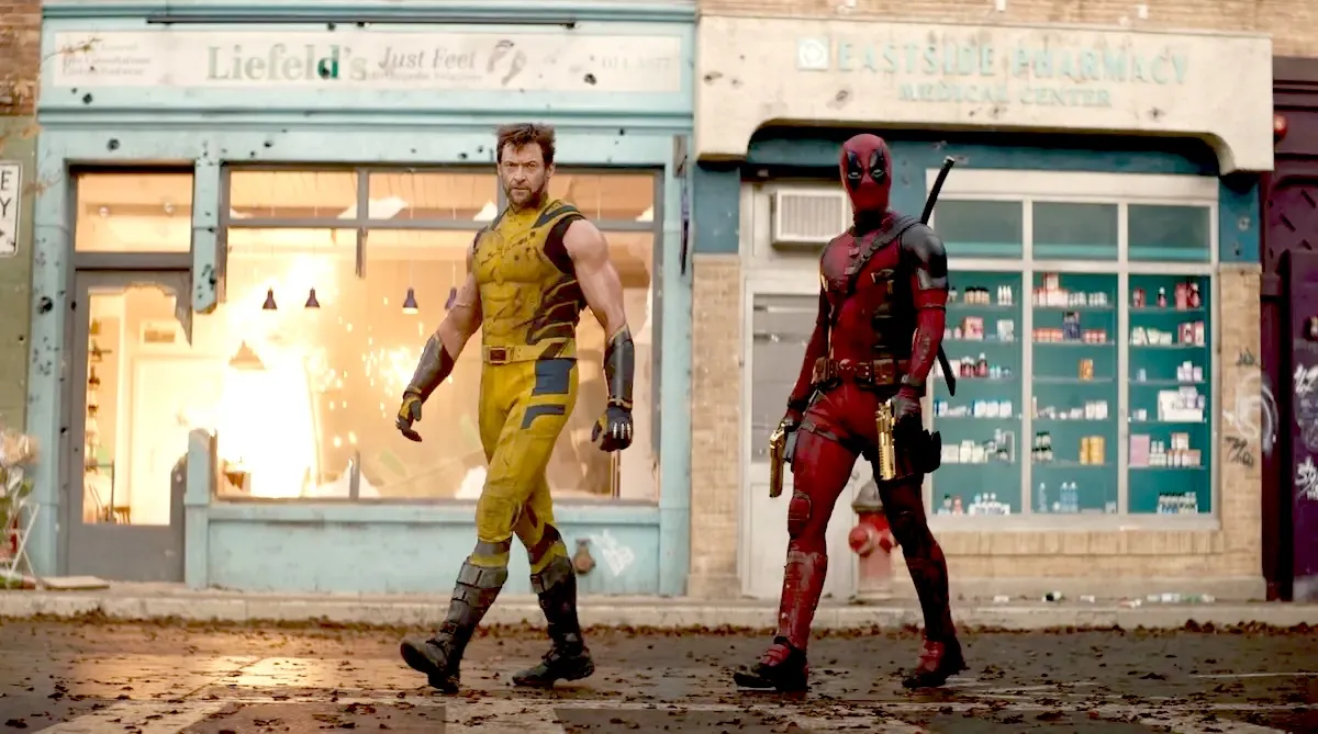 deadpool and wolverine walking in front of an explosion and store named "Liefeld's Just Feet."