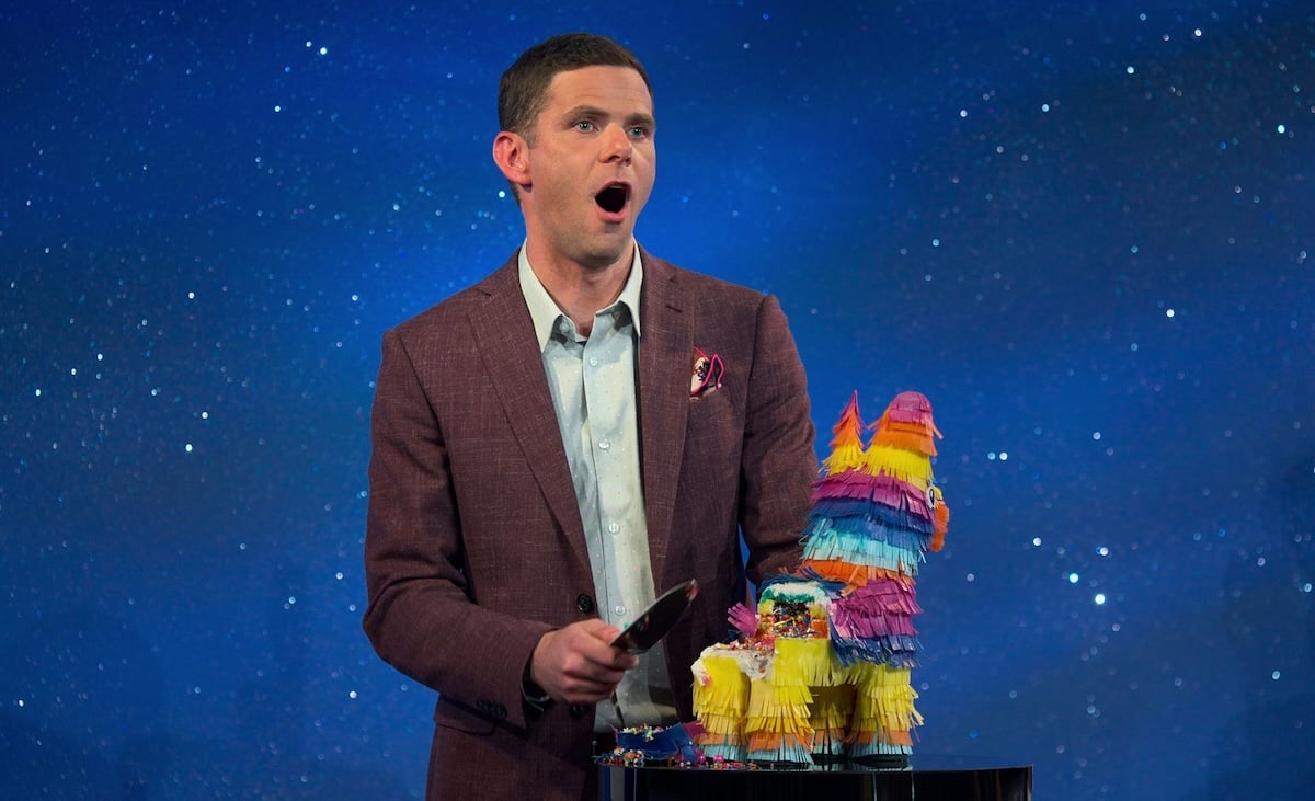Mikey Day laughs as he cuts a pinata-shaped cake.