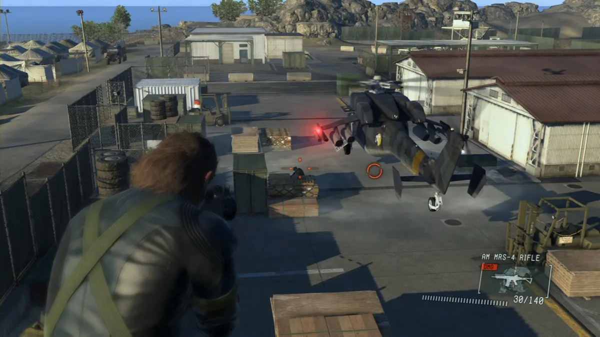 Snake sits on top of a building in a military base in "Metal Gear Solid: Ground Zeroes" 