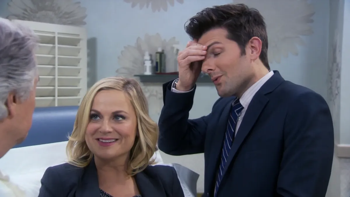 ben with his head in his hands and leslie looking excited in a hospital