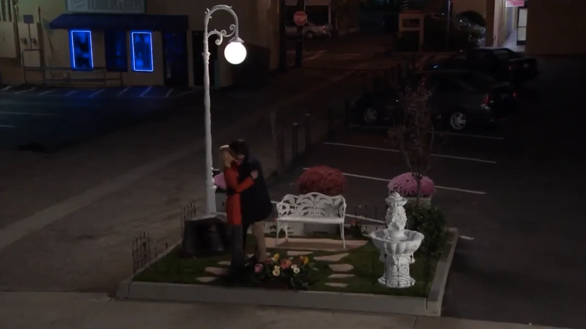 ben and leslie kissing by a bench