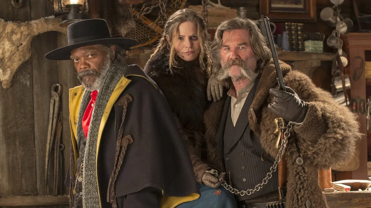 Two grizzled western men and a woman stand in a cabin with guns in "The Hateful Eight" 