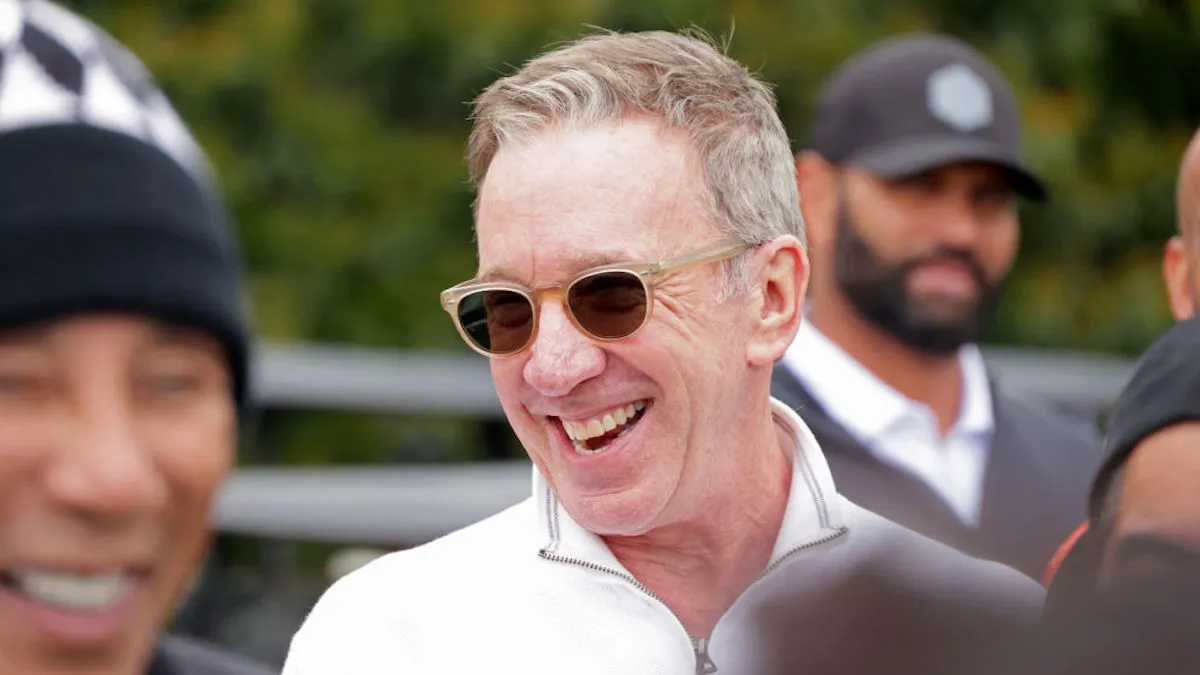 Tim Allen wears sunglasses at an outdoor event, smiling