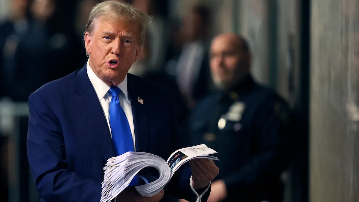 Donald Trump speaks to the media while holding news clippings